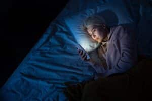 woman-in-bed_dark-room_reading-phone_freepik