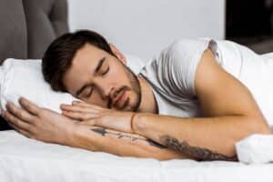 handsome-bearded-tattooed-young-man-sleeping-in-bed-2022-12-16