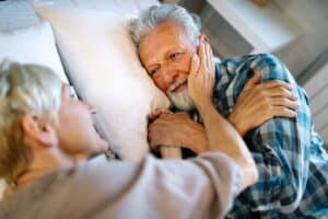 happy senior couple embracing in bed before sleeping