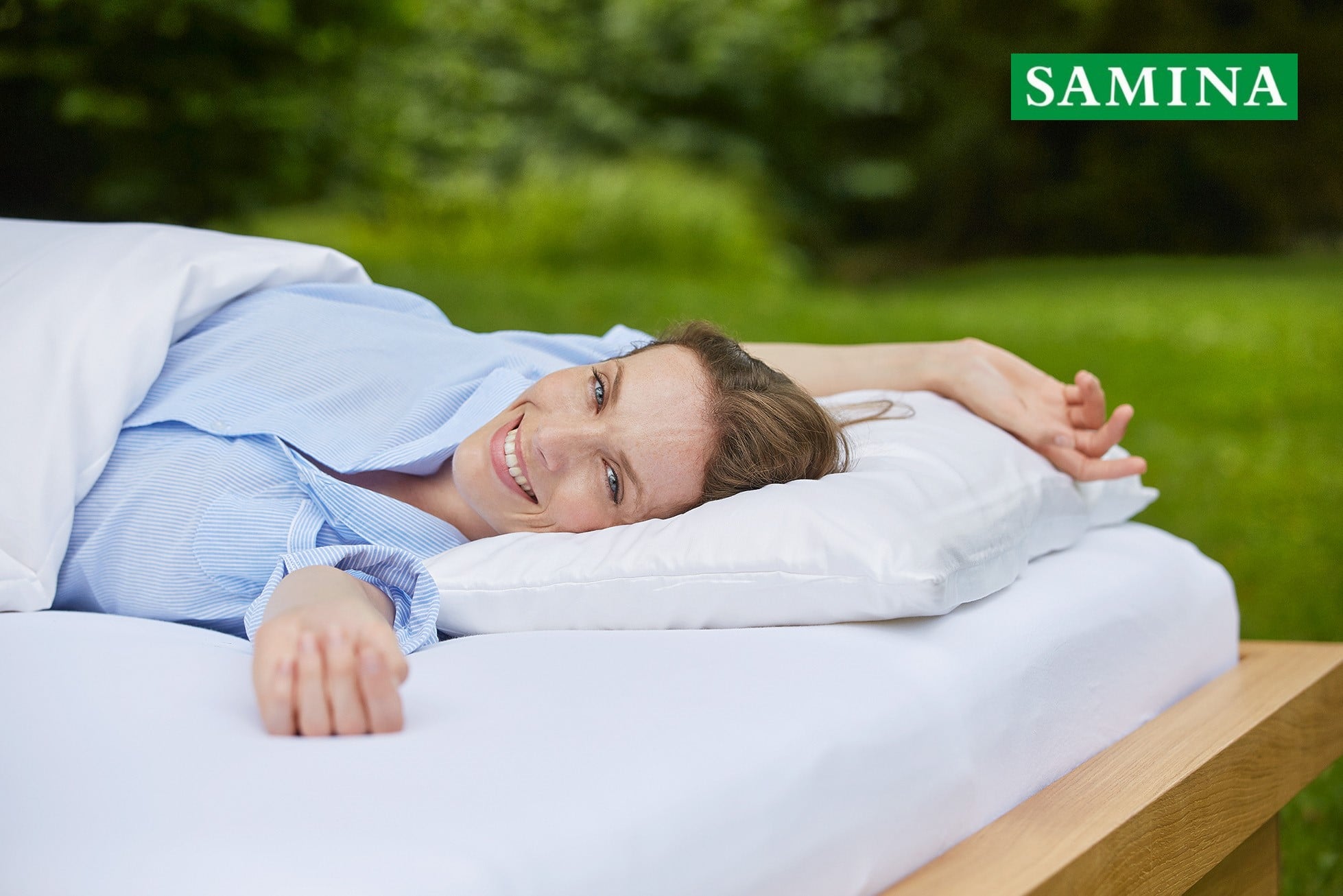 Woman lying on her back in bed smiling