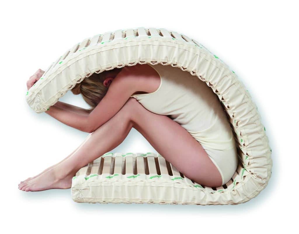 Woman seated and folding SAMINA slats over her back.