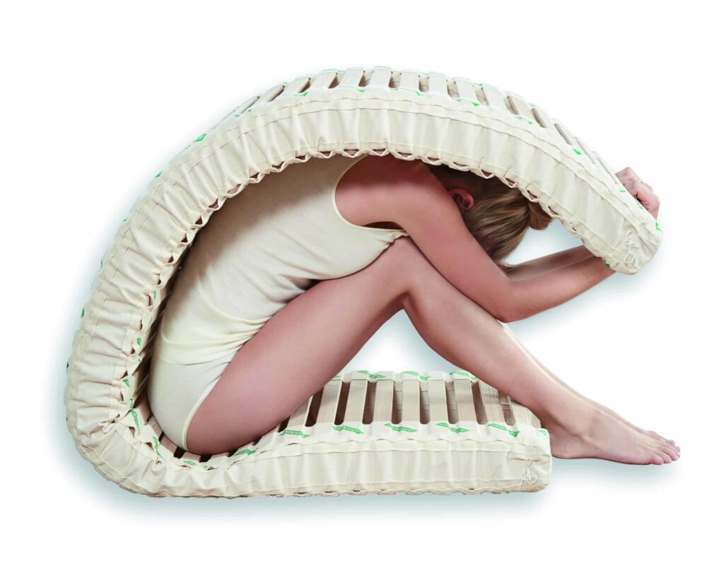 Woman seated and folding SAMINA slats over her back.