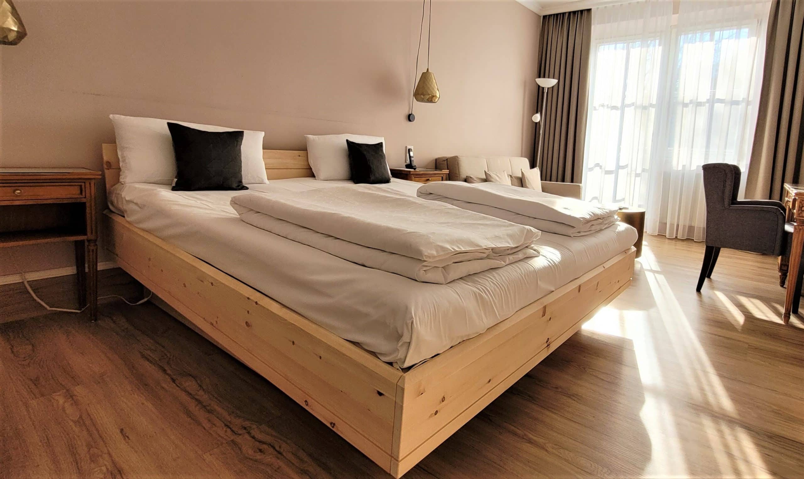 Adriano bed frame in untreated pine wood with two single duvets folded on top